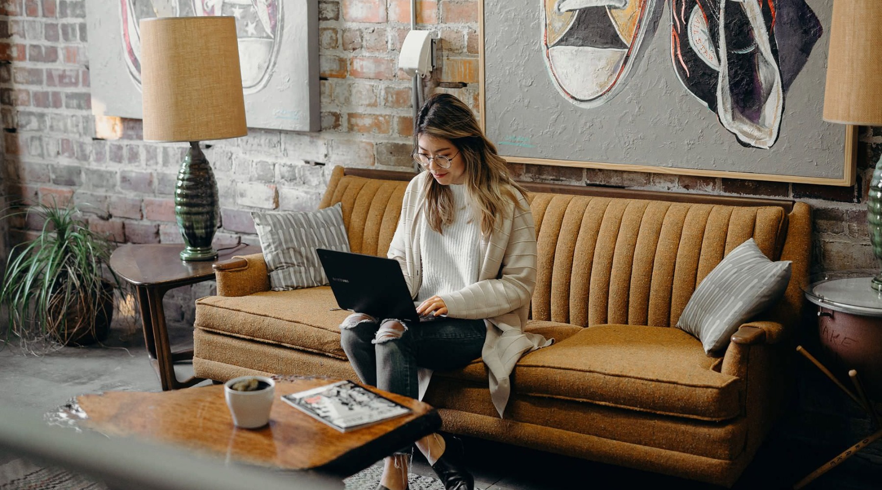 a woman sitting on a couch working on a laptop